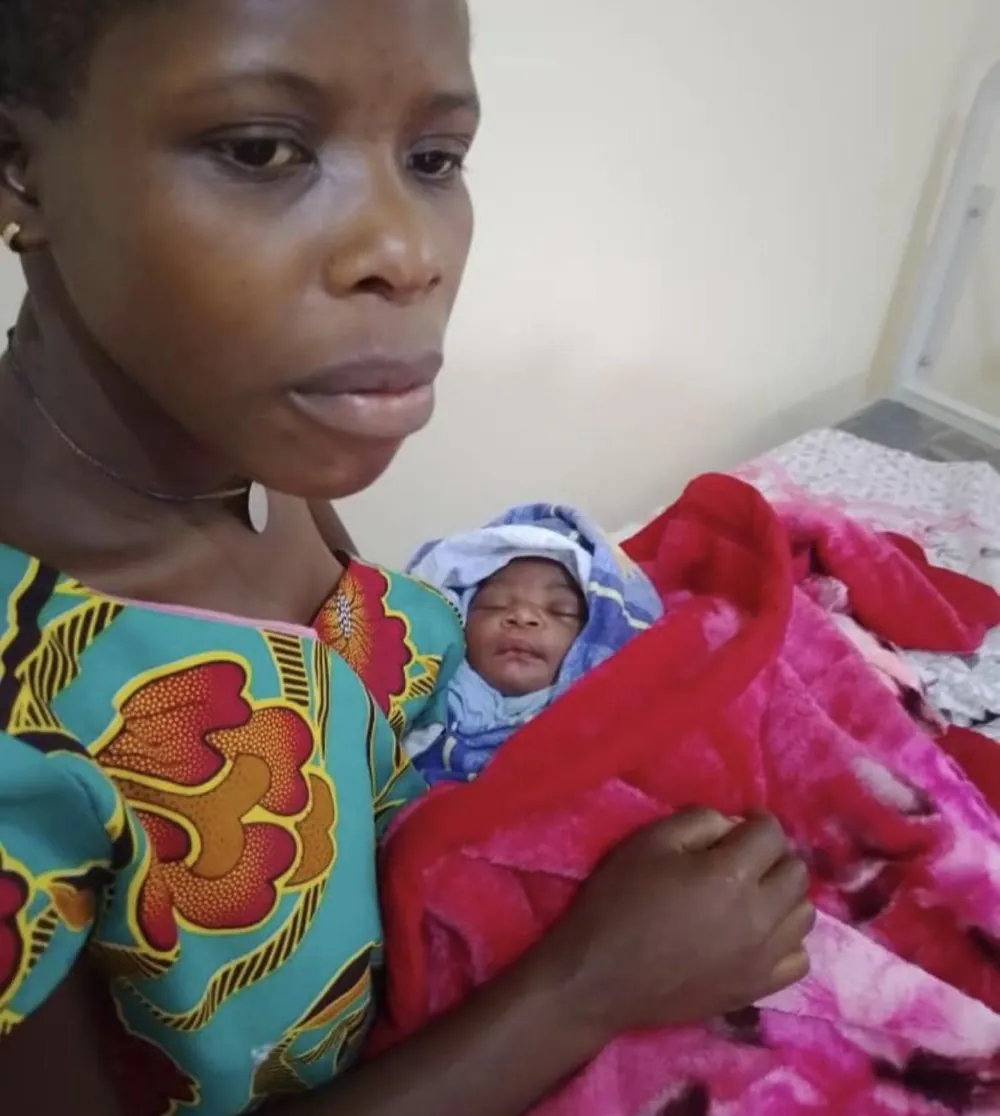 A mother holding her newborn — the first baby born at the new facility in Kyebe